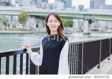 A woman walking along the river promenade while listening to music A woman walking along the river promenade while listening to music 89344336