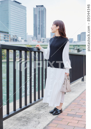 A woman walking along the river promenade while listening to music 89344346
