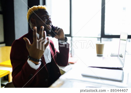 cheerful businessman entrepreneur talking mobile phone and writing note at office cheerful businessman entrepreneur talking mobile phone and writing note at office 89344407