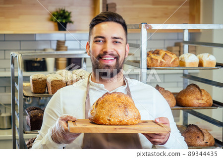 Handsome baker in uniform at the manufacturing small business owner concept 89344435