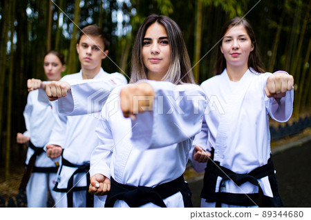 people high kicks during training of taekwondo outdoors bamboo background 89344680