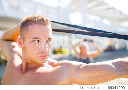couple exercises with a resistance band outdoors in tropics 89344693