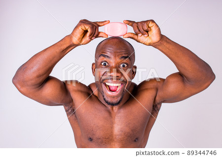 African man holds and show a piece of wet soap in studio white background 89344746
