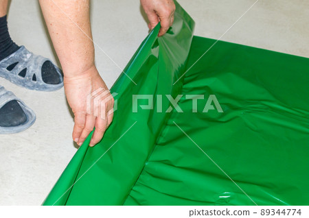 Laying green foil on the concrete floor under the sleepers before laying the floor panels. Laying green foil on the concrete floor under the sleepers before laying the floor panels. 89344774