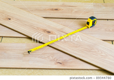Metal measuring tape on floor panels when laying them on the floor. Metal measuring tape on floor panels when laying them on the floor. 89344780