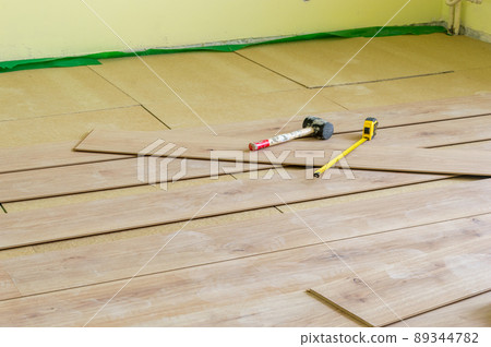 Metal measuring tape and rubber hammer on floor panels during installing floor panels. 89344782