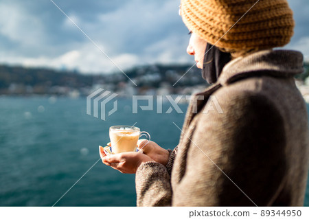 woman drinking masala tea in the front, bosphorus bay in the background woman drinking masala tea in the front, bosphorus bay in the background 89344950