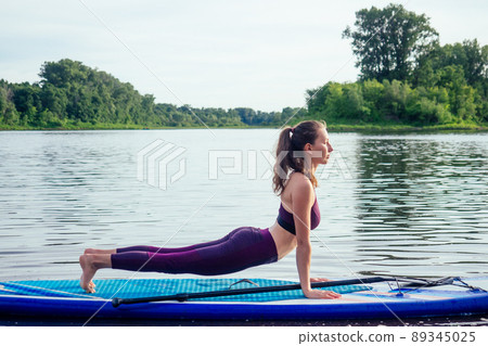 Young woman doing yoga on sup board Young woman doing yoga on sup board 89345025