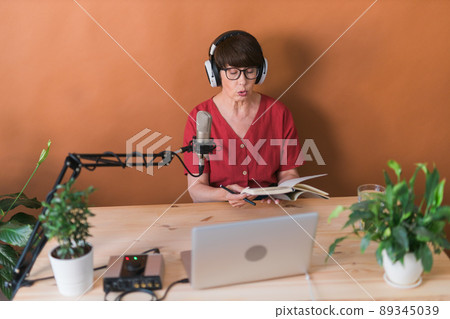 Middle-aged woman radio host making podcast recording for online show - broadcast and dj concept 89345039