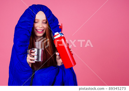 amazed and surprised redhaired ginger woman wrapped up sleeping bag and drinking hot tea in studio pink background amazed and surprised redhaired ginger woman wrapped up sleeping bag and drinking hot tea in studio pink background 89345273