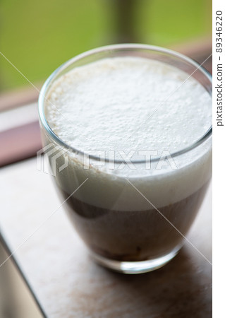 Hot coffee with milk foam in a transparent glass. Overhead view. 89346220