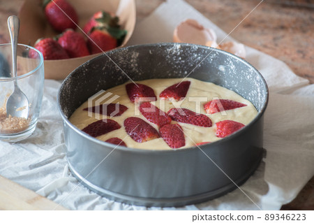 Homemade summer strawberry sponge cake in a baking form ready to bake. Homemade summer strawberry sponge cake in a baking form ready to bake. 89346223