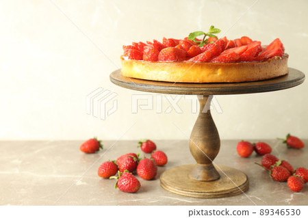 Wooden stand with strawberry tart on gray textured table 89346530