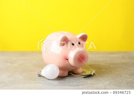 Energy saving concept with piggy bank against yellow background Energy saving concept with piggy bank against yellow background 89346725
