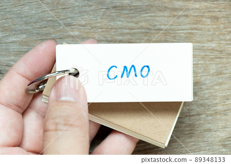 Man hold the flash card with handwriting word CMO (Abbreviation of Chief Marketing Officer, Contract Manufacturing Organization) on wood background 89348133