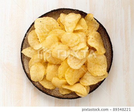 brown yellow chips from natural potato in brown ceramic plate on white wooden background 89348221