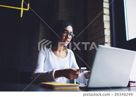 Focused African American woman working on laptop in dark workspace 89348249