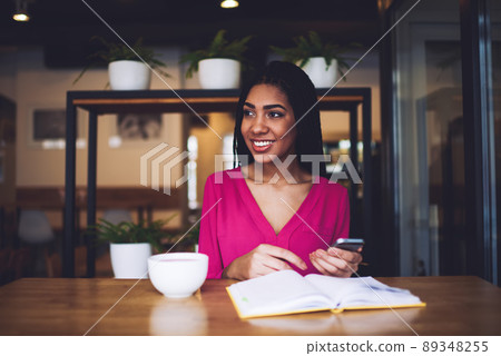Positive black female with smartphone in cafe 89348255