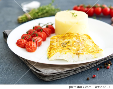Fish cod baked in oven with mashed potatoes, tomatoes, diet healthy food. Dark gray background Fish cod baked in oven with mashed potatoes, tomatoes, diet healthy food. Dark gray background 89348407