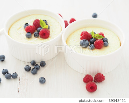 cheesecake decorated with raspberries, blueberries and mint in two ramekin, delicious dessert 89348431