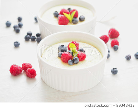 cheesecake decorated with raspberries, blueberries and mint in two ramekin, delicious dessert cheesecake decorated with raspberries, blueberries and mint in two ramekin, delicious dessert 89348432