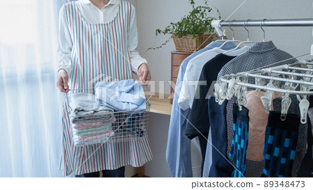 A woman hanging up laundry in the room 89348473