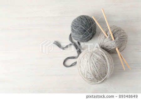 Yarn balls and knitting needles on white wooden table 89348649