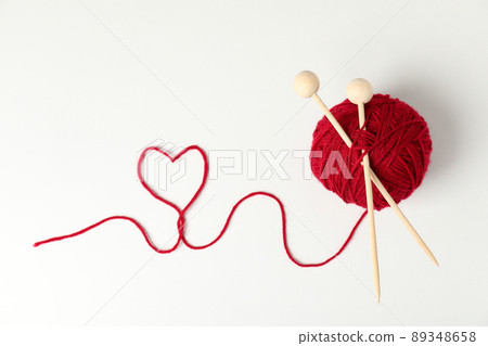 Red ball of yarn and knitting needles on white background 89348658