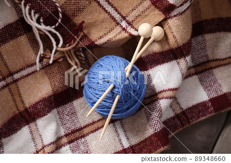 Ball of yarn with knitting needles on checkered plaid Ball of yarn with knitting needles on checkered plaid 89348660