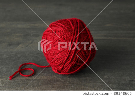 Red yarn ball on gray wooden table 89348665
