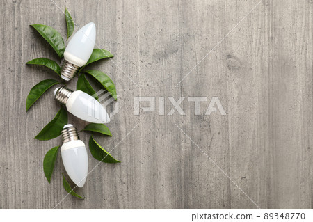 Energy saving bulbs with leaves on gray textured background Energy saving bulbs with leaves on gray textured background 89348770