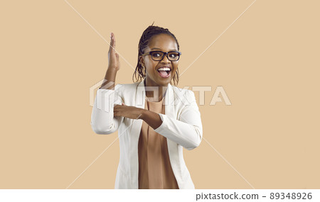 Woman raises her hand to attract attention and answer questions isolated on beige background. 89348926