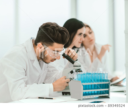 close up.man scientist looking through a microscope close up.man scientist looking through a microscope 89349324