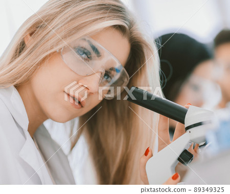 close up.a modern female scientist looks into a microscope in a 89349325