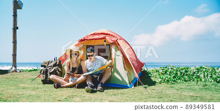 Male and female sitting in tent near sea Male and female sitting in tent near sea 89349581
