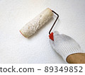 Male hand painting wall with roller. Renovating with white color paint 89349852