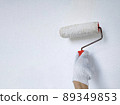 Male hand painting wall with roller. Renovating with white color paint 89349853