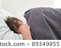 Man sleeping in bed under blanket in the morning.  89349855