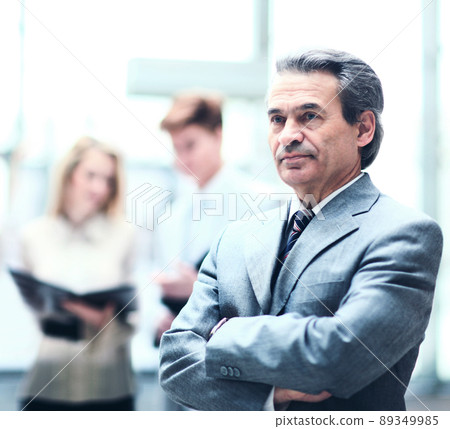 Happy smart business man with team mates discussing in the background in the office Happy smart business man with team mates discussing in the background in the office 89349985