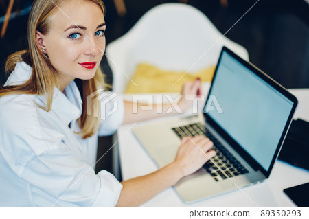 Smiling woman typing on laptop in office 89350293