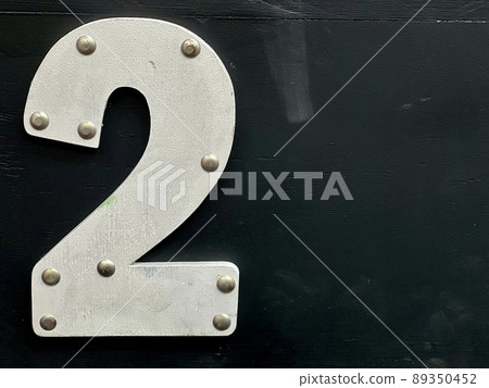 White wooden number two with nail heads on black background, copy space for your text. White wooden number two with nail heads on black background, copy space for your text. 89350452