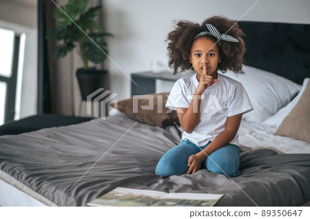 A sweet girl showing silence sign and looking excited A sweet girl showing silence sign and looking excited 89350647