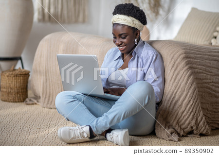 Dark-skinned smiling woman witha laptop 89350902