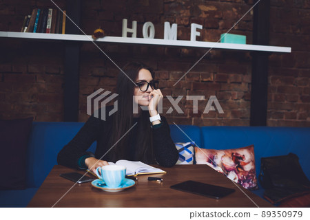 Glad woman with book resting in cafe 89350979