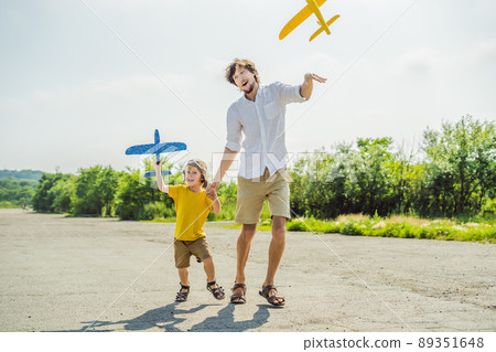 Happy father and son playing with toy airplane against old runway background. Traveling with kids concept 89351648