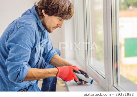 Man in a blue shirt does window installation 89351988