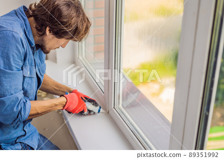 Man in a blue shirt does window installation 89351992