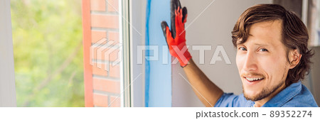 Man in a blue shirt does window installation BANNER, LONG FORMAT Man in a blue shirt does window installation BANNER, LONG FORMAT 89352274