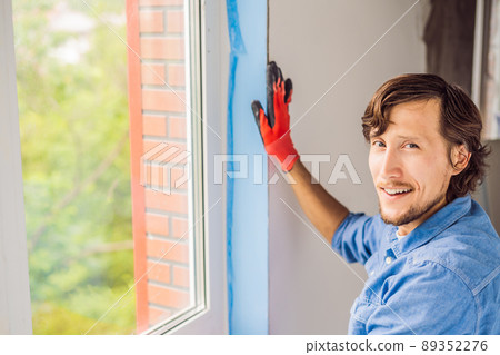 Man in a blue shirt does window installation Man in a blue shirt does window installation 89352276