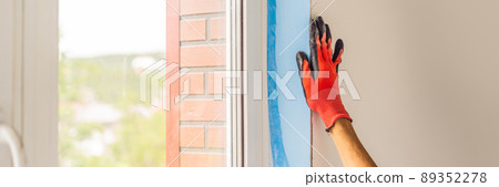 Man in a blue shirt does window installation BANNER, LONG FORMAT 89352278